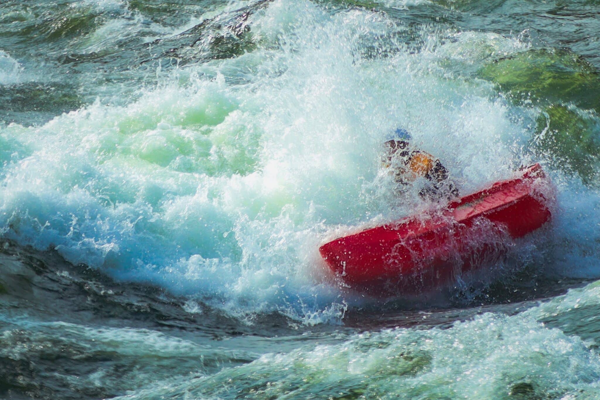 Solo canoeing side surfing big white water splash